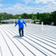 Single Roofer Walking On Flat Metal Roof