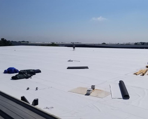 Wide View Of Single Roofer On Large Flat White Roof