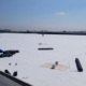 Wide View Of Single Roofer On Large Flat White Roof